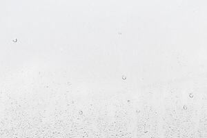 Rain drops on window glasses surface with gray sky background . Natural backdrop of raindrops. Abstract overlay for design. The concept of rainy weather. photo