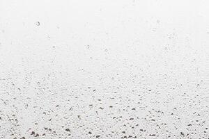 Rain drops on window glasses surface with gray sky background . Natural backdrop of raindrops. Abstract overlay for design. The concept of rainy weather. photo