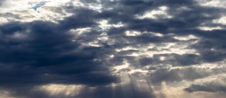 Sun rays breaking through cumulus clouds. The concept of divine light, a glimmer of hope or overcoming difficulties. Spiritual religious background. photo