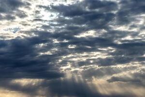 Sun rays breaking through cumulus clouds. The concept of divine light, a glimmer of hope or overcoming difficulties. Spiritual religious background. photo