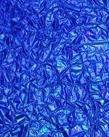 Texture of crumpled aluminum kitchen foil with reflected violet and green light. photo