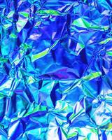 Texture of crumpled aluminum kitchen foil with reflected violet and green light. photo