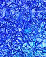 Texture of crumpled aluminum kitchen foil with reflected violet and green light. photo