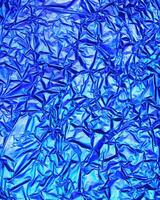 Texture of crumpled aluminum kitchen foil with reflected violet and green light. photo