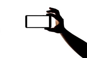 Silhouette of hand with smartphone taking picture isolated on white background. Screen with copy space. Blank for design. photo