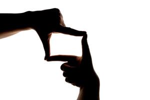Silhouette of hand showing photo frame gesture isolated on white background. Blank for design.