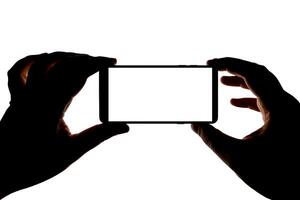 Silhouette of hands with smartphone taking picture isolated on white background. Screen with copy space. Blank for design. photo