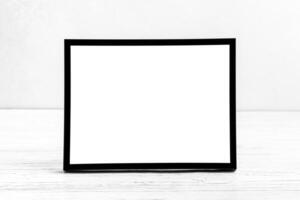 White wooden floor over concrete or decorative plaster wall and black photo frame with copy space for a text background. Mock up.
