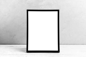 White wooden floor over concrete or decorative plaster wall and black photo frame with copy space for a text background. Mock up.
