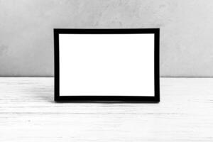 White wooden floor over concrete or decorative plaster wall and black photo frame with copy space for a text background. Mock up.