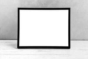 White wooden floor over concrete or decorative plaster wall and black photo frame with copy space for a text background. Mock up.