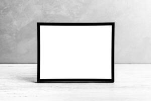 White wooden floor over concrete or decorative plaster wall and black photo frame with copy space for a text background. Mock up.