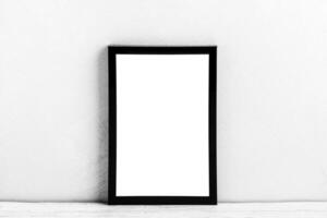 White wooden floor over concrete or decorative plaster wall and black photo frame with copy space for a text background. Mock up.