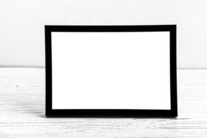 White wooden floor over concrete or decorative plaster wall and black photo frame with copy space for a text background. Mock up.