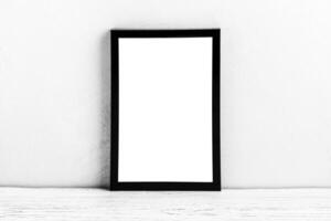 White wooden floor over concrete or decorative plaster wall and black photo frame with copy space for a text background. Mock up.