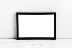 White wooden floor over concrete or decorative plaster wall and black photo frame with copy space for a text background. Mock up.