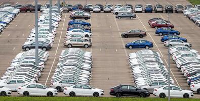 Rows of a new cars parked in a distribution center on a cloudy day in the spring, a car factory. Top view to the parking in the open air. photo