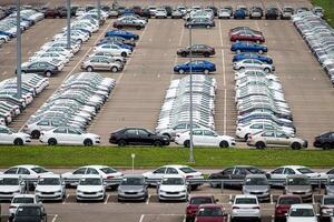 Rows of a new cars parked in a distribution center of a car factory. Top view to the parking in the open air. photo