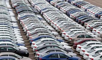 Rows of a new cars parked in a distribution center on a cloudy day in the spring, a car factory. Top view to the parking in the open air. photo