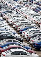 Rows of a new cars parked in a distribution center on a cloudy day in the spring, a car factory. Top view to the parking in the open air. photo
