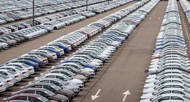 Rows of a new cars parked in a distribution center on a car factory on a cloudy day. Top view to the parking in the open air. photo