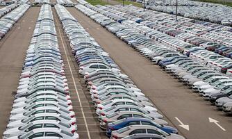 Rows of a new cars parked in a distribution center of a car factory. Top view to the parking in the open air. photo