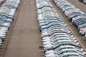 Rows of a new cars parked in a distribution center of a car factory. Top view to the parking in the open air. photo