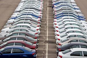 Rows of a new cars parked in a distribution center of a car factory. Top view to the parking in the open air. photo