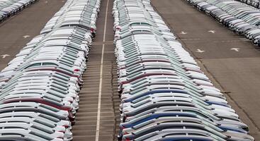 Rows of a new cars parked in a distribution center of a car factory. Top view to the parking in the open air. photo