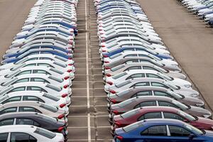 Rows of a new cars parked in a distribution center on a car factory on a cloudy day. Top view to the parking in the open air. photo