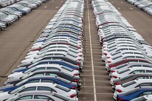 Rows of a new cars parked in a distribution center on a car factory on a cloudy day. Top view to the parking in the open air. photo