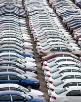 Rows of a new cars parked in a distribution center of a car factory. Top view to the parking in the open air. photo