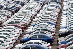 Rows of a new cars parked in a distribution center on a cloudy day in the spring, a car factory. Top view to the parking in the open air. photo