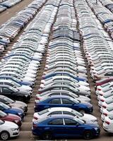 Rows of a new cars parked in a distribution center on a cloudy day in the spring, a car factory. Top view to the parking in the open air. photo