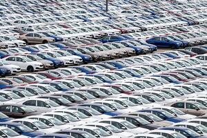 Rows of a new cars parked in a distribution center on a cloudy day in the spring, a car factory. Top view to the parking in the open air. photo