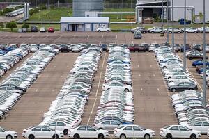 Volkswagen Group Rus, Russia, Kaluga - MAY 24, 2020 Rows of a new cars parked in a distribution center on a cloudy day in the spring and a car factory buildings. Parking in the open air. photo