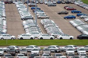 Volkswagen Group Rus, Russia, Kaluga - MAY 24, 2020 Rows of a new cars parked in a distribution center. Top view to the parking in the open air. photo