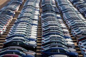 Rows of a new cars parked in a distribution center on a car factory on a sunny day. Top view to the parking in the open air. photo