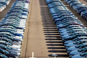Rows of a new cars parked in a distribution center on a car factory on a sunny day. Top view to the parking in the open air. photo