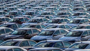 Rows of a new cars parked in a distribution center on a car factory on a sunny day. Top view to the parking in the open air. photo