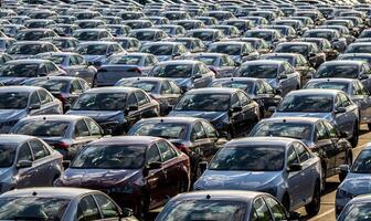 Rows of a new cars parked in a distribution center on a car factory on a sunny day. Top view to the parking in the open air. photo
