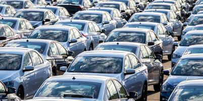 Rows of a new cars parked in a distribution center on a car factory on a sunny day. Top view to the parking in the open air. photo