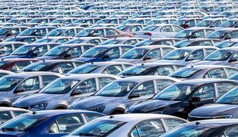 Rows of a new cars parked in a distribution center on a car factory on a sunny day. Top view to the parking in the open air. photo