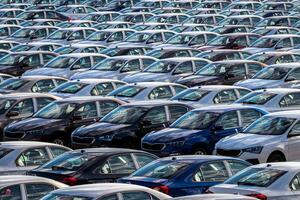 Rows of a new cars parked in a distribution center on a car factory on a sunny day. Parking in the open air. photo