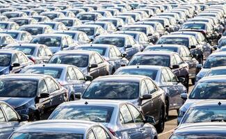 Rows of a new cars parked in a distribution center on a car factory on a sunny day. Top view to the parking in the open air. photo