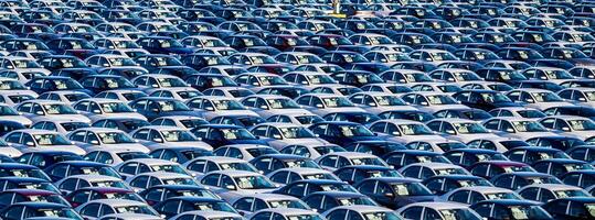 Rows of a new cars parked in a distribution center on a car factory on a sunny day. Parking in the open air. photo