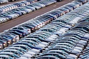 Rows of a new cars parked in a distribution center on a car factory on a sunny day. Top view to the parking in the open air. photo