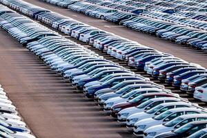 Rows of a new cars parked in a distribution center on a car factory on a sunny day. Parking in the open air. photo