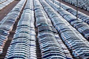 Rows of a new cars parked in a distribution center on a car factory on a sunny day. Parking in the open air. photo