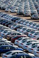 Volkswagen Group Rus, Russia, Kaluga - MAY 25, 2020 Rows of a new cars parked in a distribution center on a sunny day in the spring. Top view to a parking in the open air. photo